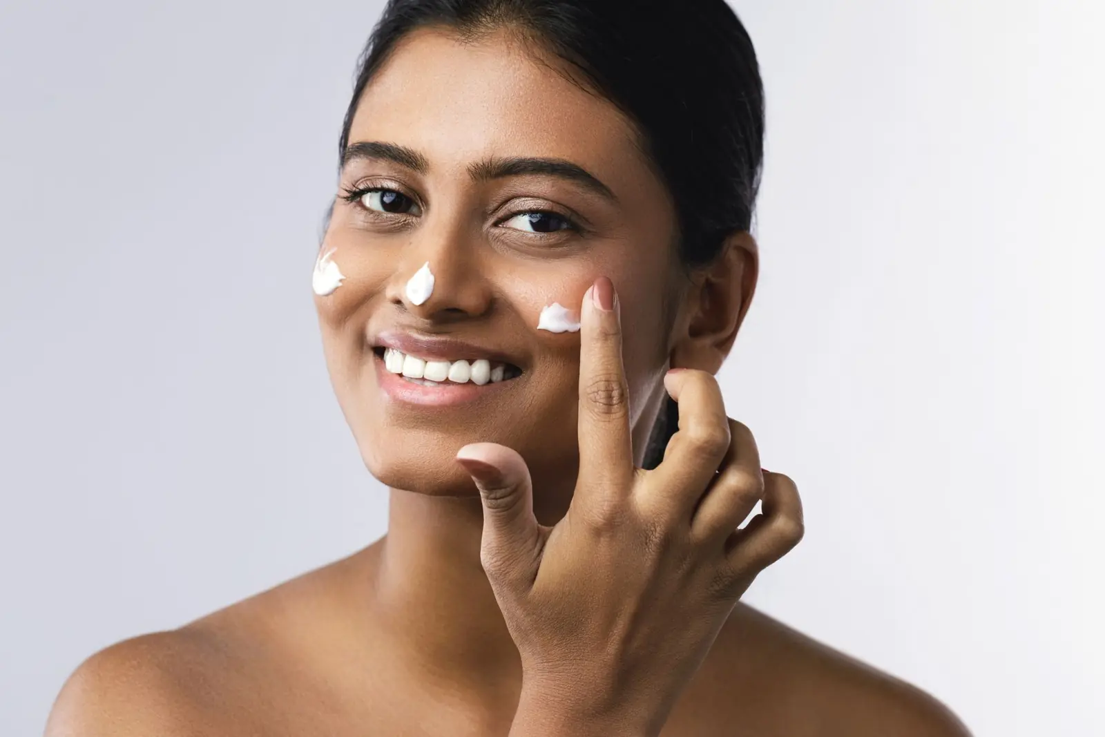 Woman applying moisturiser at home